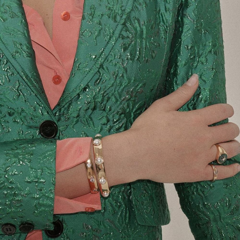 Gold bracelets against a green brocade jacket